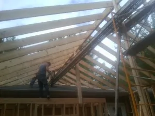 Rafters going up over a new addition with a worker on the wall in Gilson