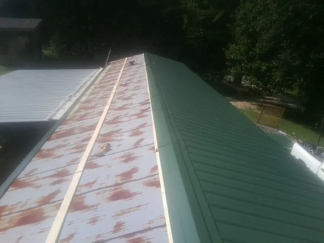 Old rusted panels beside newly installed green metal roofing — Wind Damage Roof Repair by Roofing Brothers in Gilson