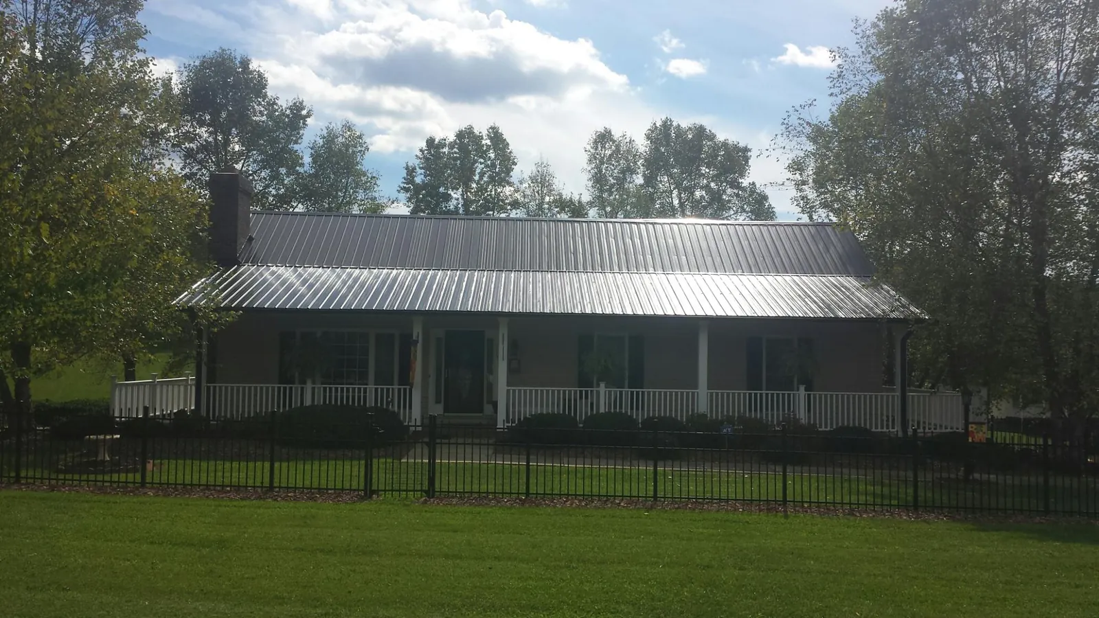 Gray metal roof on a brick ranch with a full width front porch — Gutter Guard Installation work by our crew in Gilson