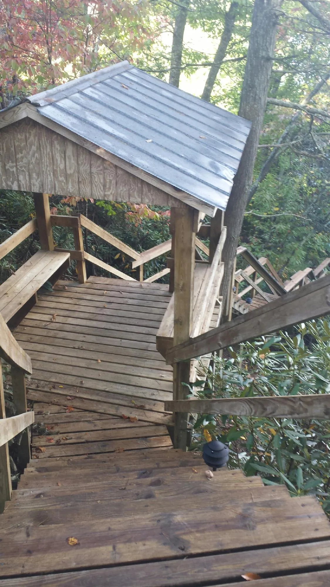 Metal roofed shelter over wooden steps on a wooded walkway — Skylight Repair & Installation work by our crew in Gilson